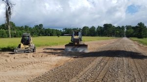 Track loader with powerbox rake and bulldozer grading roadway